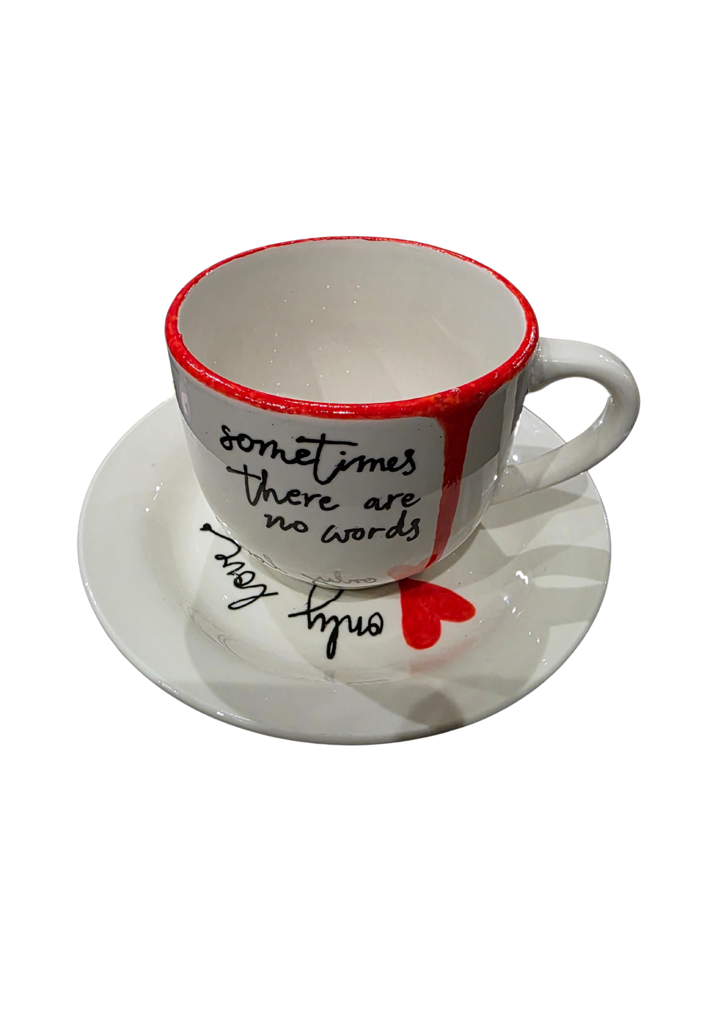 Ceramic cup and saucer with red interior, black text, and red heart on a white background